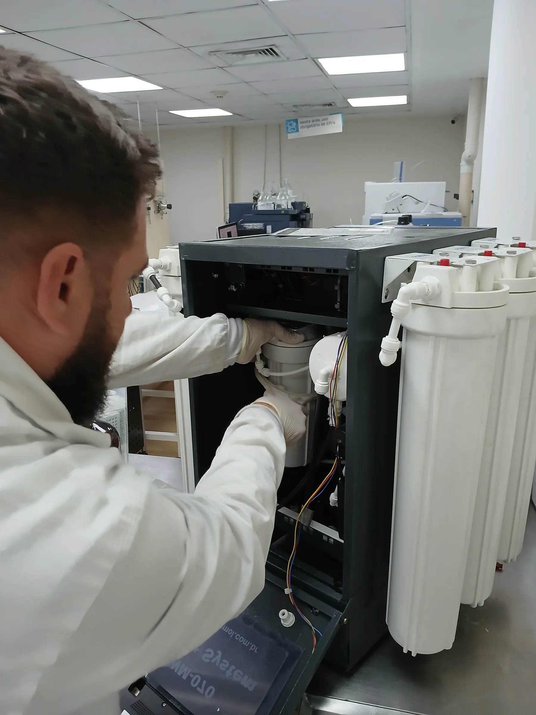 Mãos com luvas brancas em manutenção interna de equipamento de água ultrapura