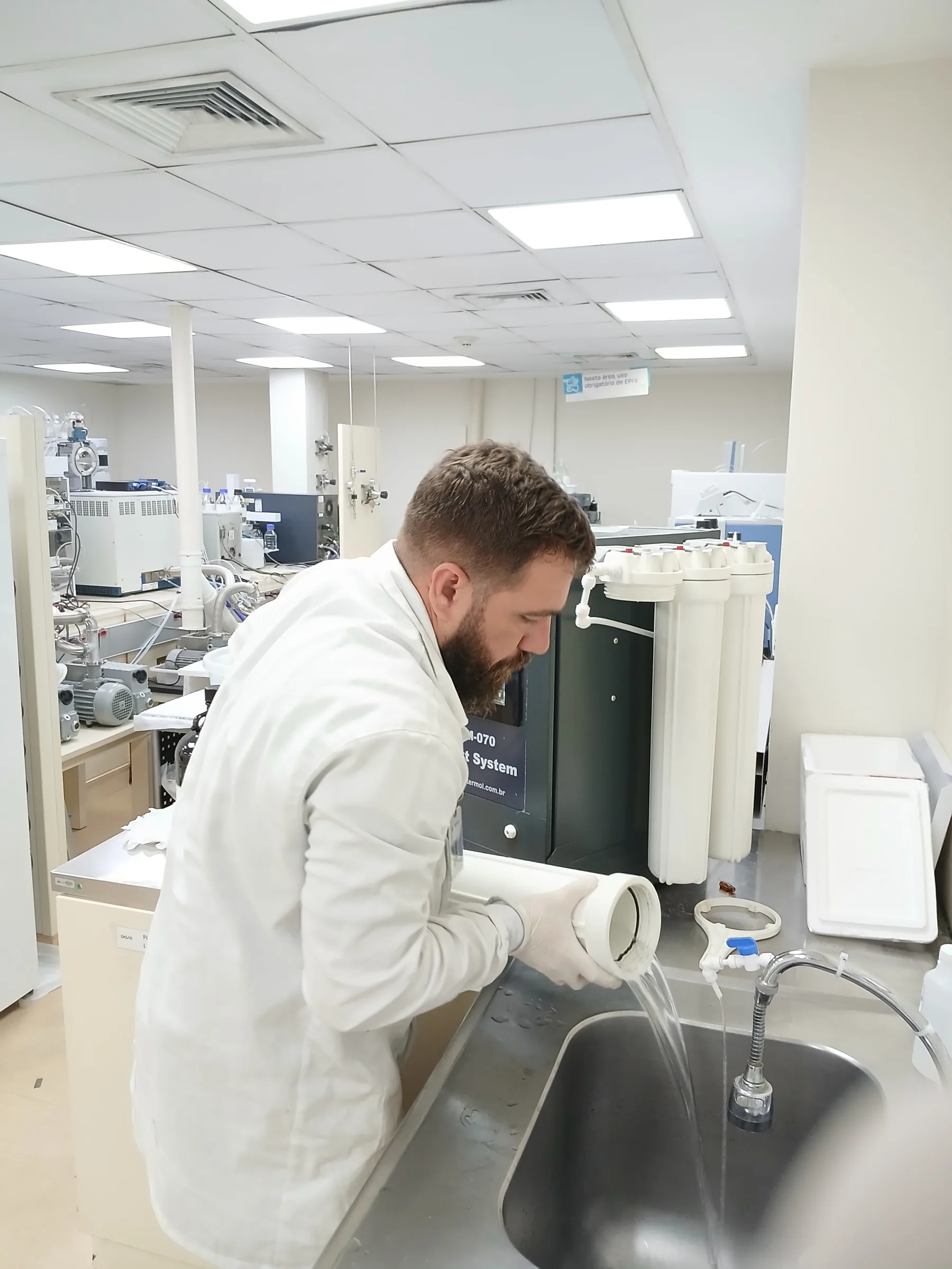Técnico de jaleco em laboratório clínico próximo a sistema de produção de água