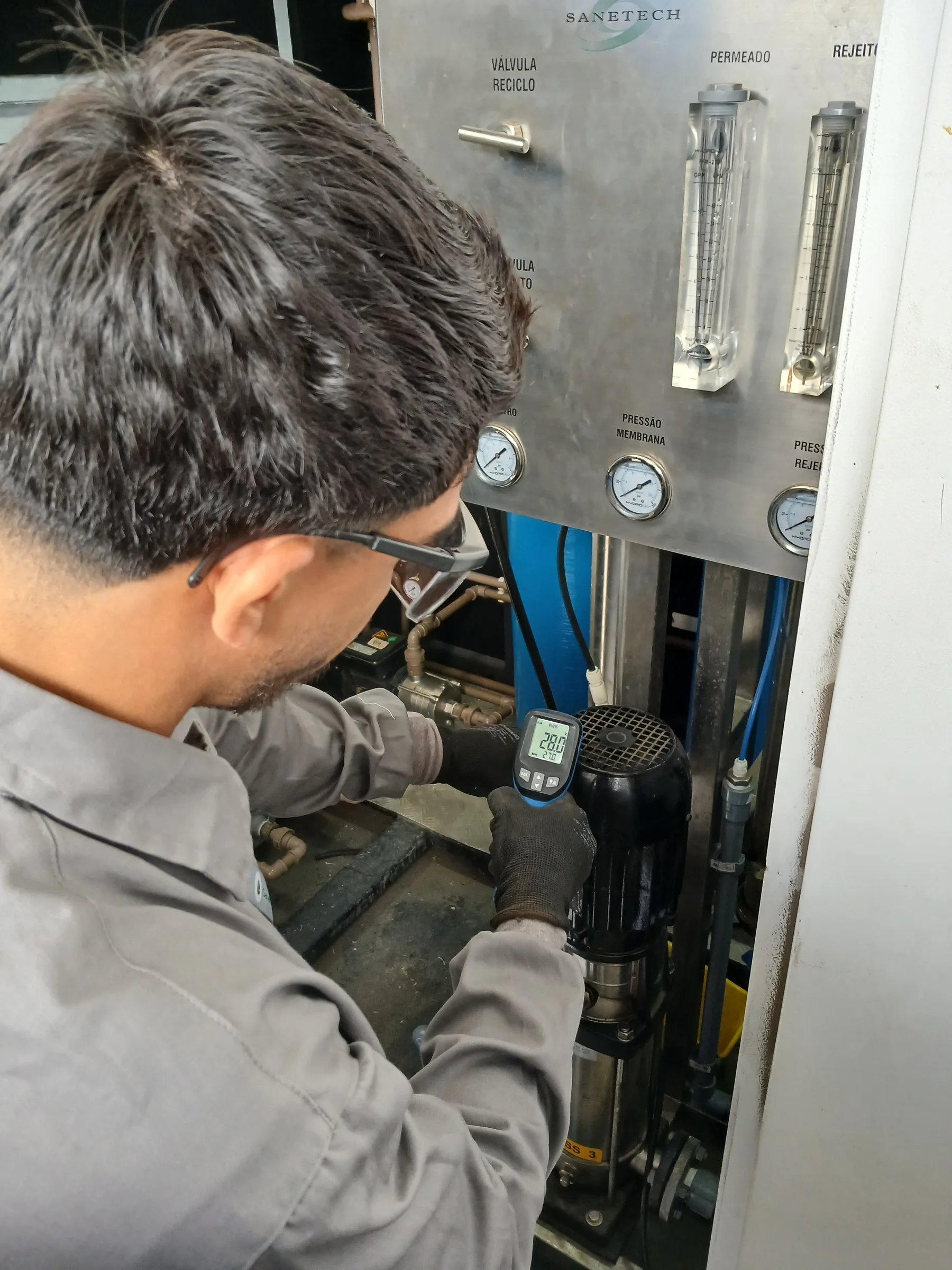 Técnico fazendo leitura com multímetro em painel de controle de sistema de reuso