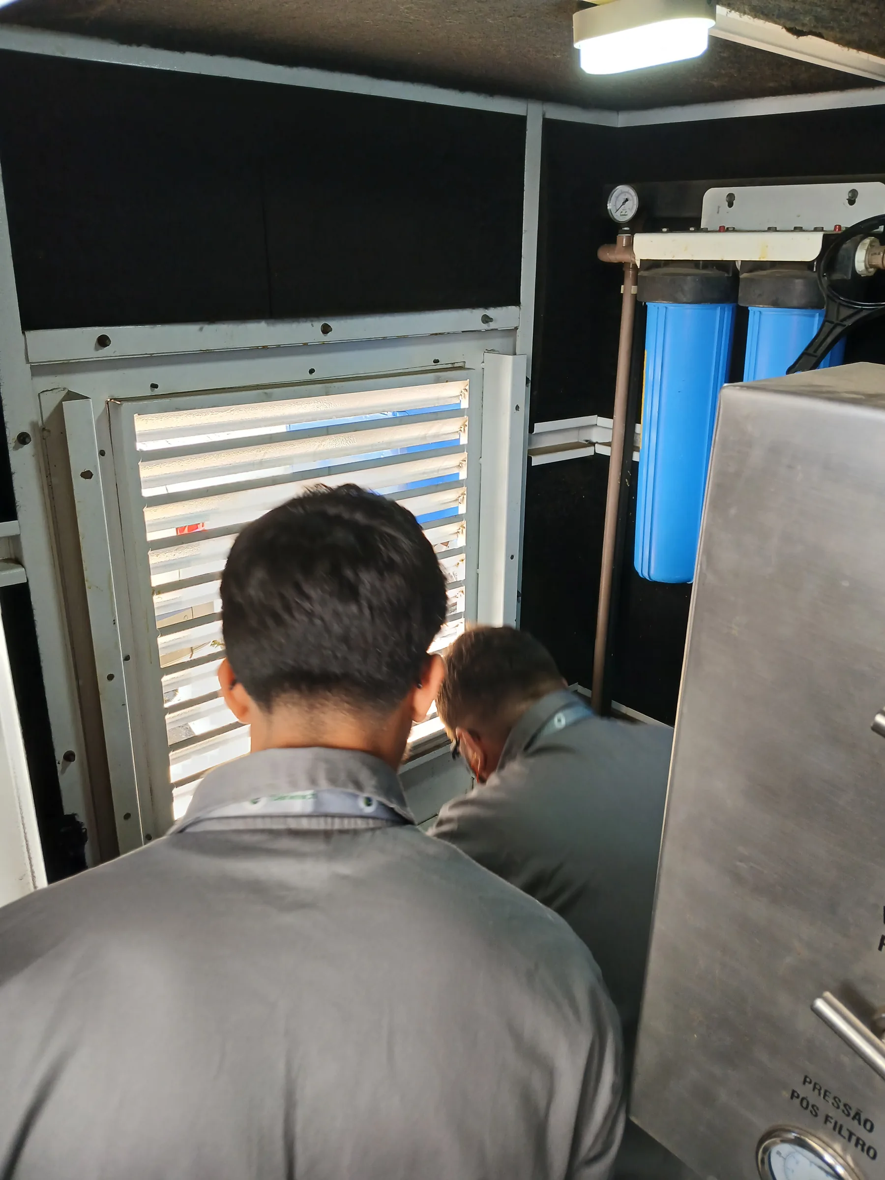 Técnicos inspecionando filtro azul de sistema de reuso de água