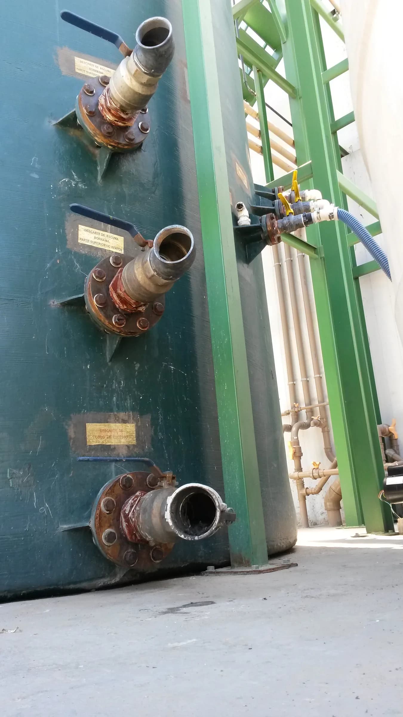 Closeup de flanges metálicos com conexões enferrujadas em tanque externo verde