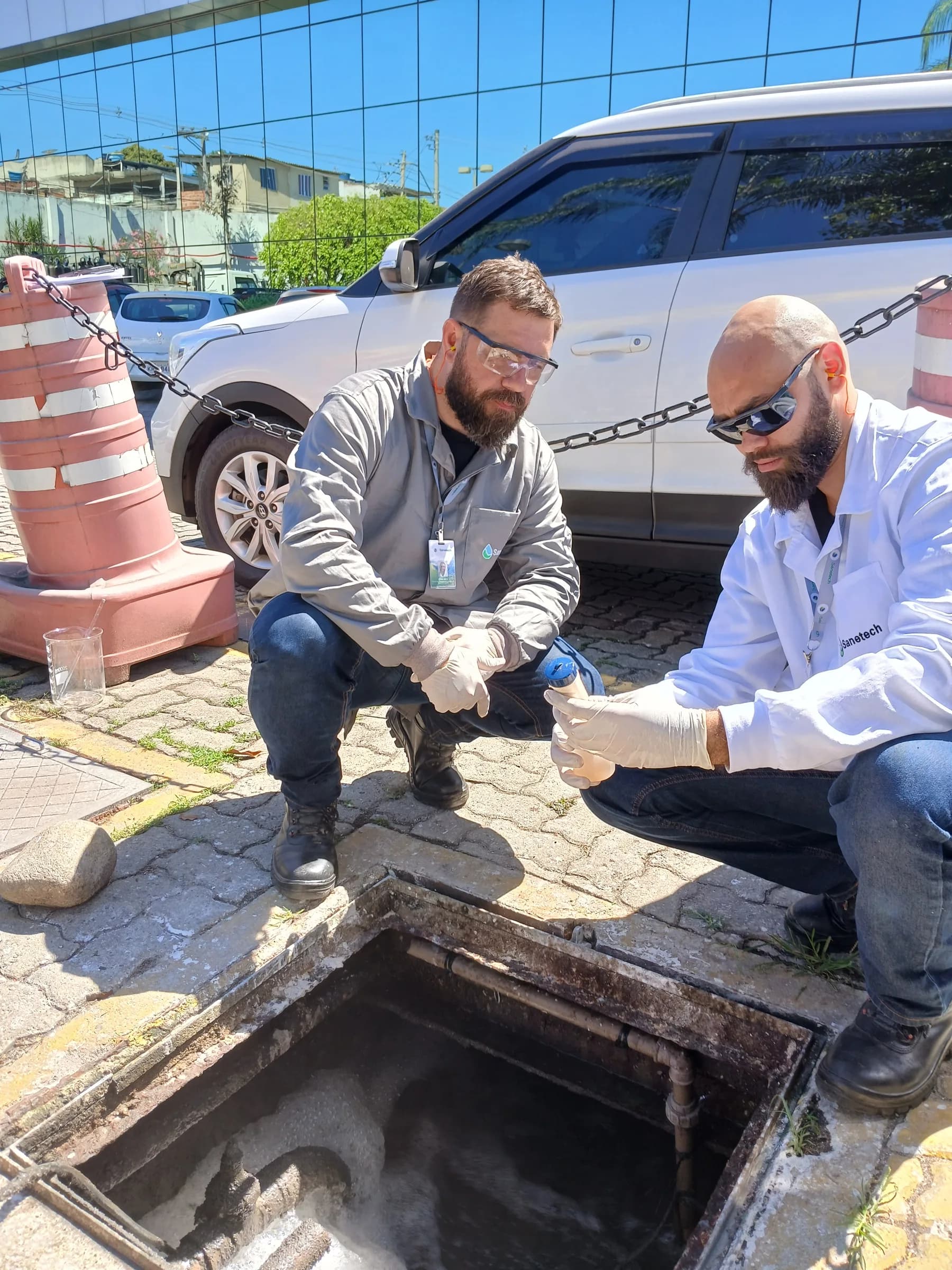 Dois técnicos abrindo escotilha de inspeção de poço de visita em ETDI